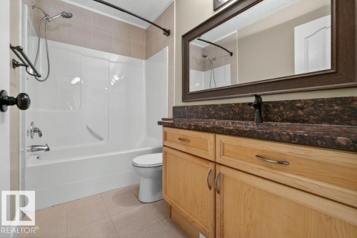 Bathroom featuring a vanity with wood cabinetry, dark speckled countertop, and an undermount sink - 10 Erickson Close, St. Albert, AB - Indoor Photo Showing Bathroom