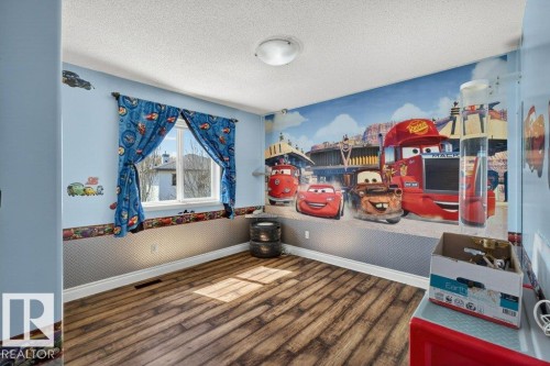 Bright interior space featuring wood-finish flooring, light blue painted walls, and a white ceiling with a flush-mount light fixture - 10 Erickson Close, St. Albert, AB - Indoor Photo Showing Other Room