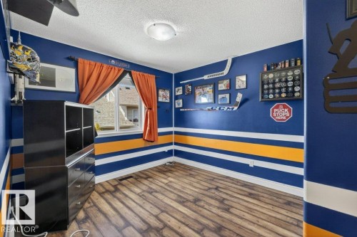 Room featuring wood-finish flooring, a ceiling-mounted light fixture, and a window with orange drapes - 10 Erickson Close, St. Albert, AB - Indoor Photo Showing Other Room
