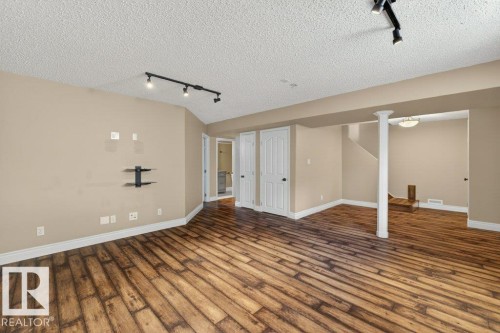 Spacious finished basement featuring wood-finish flooring, neutral wall tones, and track lighting - 10 Erickson Close, St. Albert, AB - Indoor Photo Showing Other Room