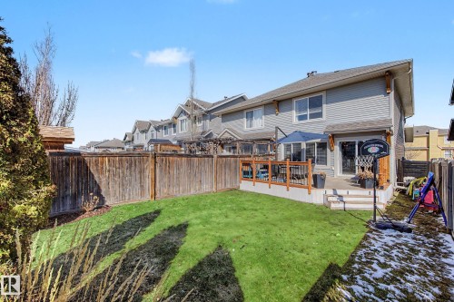 Expansive backyard featuring a tiered wood deck, mature perimeter fencing, and a manicured lawn area - 2083 Chalmers Way, Edmonton, AB - Outdoor With Deck Patio Veranda