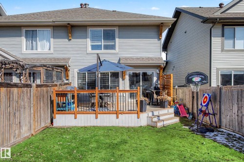Rear exterior featuring a wooden deck with black metal railings, a sliding glass door, and vinyl siding - 2083 Chalmers Way, Edmonton, AB - Outdoor With Exterior