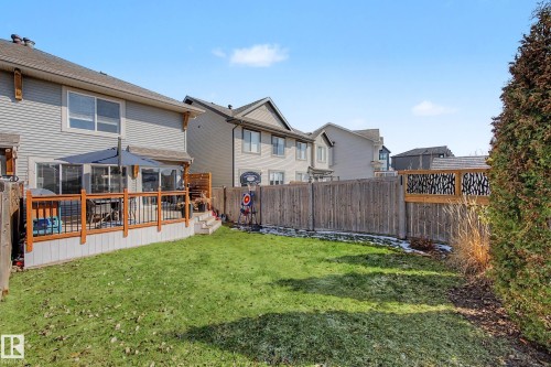 Fenced backyard featuring a manicured lawn, multi-level wood deck with black metal railings, and a decorative privacy screen - 2083 Chalmers Way, Edmonton, AB - Outdoor With Deck Patio Veranda