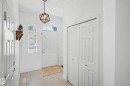 Entryway featuring light-toned tile flooring, a geometric pendant light fixture, and a white paneled entry door with an overhead transom window - 2083 Chalmers Way, Edmonton, AB  - Indoor Photo Showing Other Room 