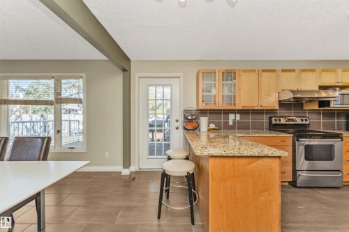 Kitchen featuring stainless steel appliances, light wood cabinetry, and a granite-style countertop - 6016 177 Street, Edmonton, AB - Indoor Photo Showing Kitchen