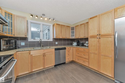 Kitchen featuring light wood cabinetry, granite-finish countertops, and stainless steel appliances - 6016 177 Street, Edmonton, AB - Indoor Photo Showing Kitchen With Stainless Steel Kitchen