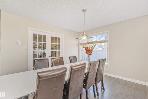 Dining area with durable tiled flooring and a contemporary pendant light fixture - 6016 177 Street, Edmonton, AB - Indoor Photo Showing Dining Room