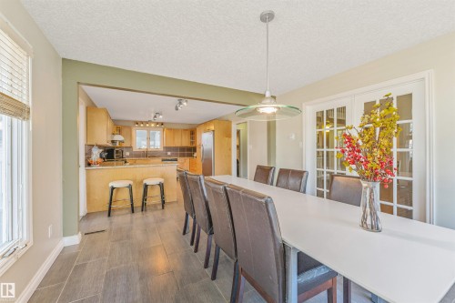 Dining area featuring tile flooring, a modern pendant light fixture, and double glass-paneled doors - 6016 177 Street, Edmonton, AB - Indoor Photo Showing Dining Room