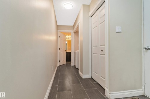 Hallway featuring rectangular floor tiles and light-toned walls - 6016 177 Street, Edmonton, AB - Indoor Photo Showing Other Room