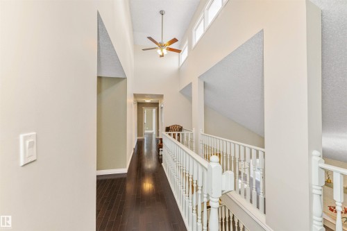 Two-story entryway with dark wood-finish flooring, a white spindle staircase, and a ceiling fan with integrated lighting - 6016 177 Street, Edmonton, AB - Indoor Photo Showing Other Room