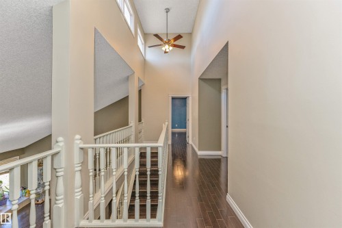 Upper-level hallway featuring high ceilings, dark wood-finish flooring, white spindle railings, and a ceiling fan - 6016 177 Street, Edmonton, AB - Indoor Photo Showing Other Room