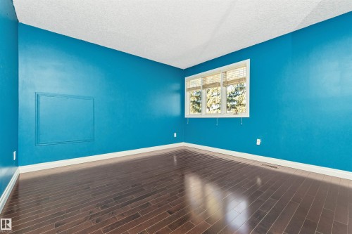 Room featuring wood-finish flooring, a white-framed window with blinds, and white baseboards - 6016 177 Street, Edmonton, AB - Indoor Photo Showing Other Room