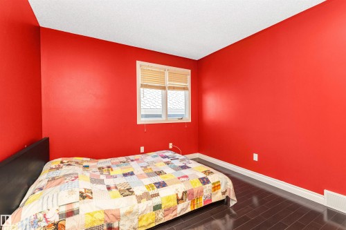 Bedroom featuring red painted walls, dark wood-finish flooring, a white ceiling, and a single window with blinds - 6016 177 Street, Edmonton, AB - Indoor Photo Showing Bedroom