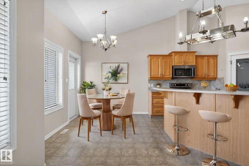Open-concept kitchen and dining area featuring light wood cabinetry, a built-in microwave, and an eat-at breakfast bar - 34 3003 34 Avenue, Edmonton, AB - Indoor