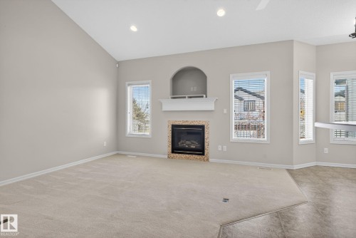 Spacious living area featuring a fireplace with a tiled surround and white mantel, vaulted ceiling with recessed lighting, multiple windows with blinds, and a combination of carpet and tiled flooring - 34 3003 34 Avenue, Edmonton, AB - Indoor Photo Showing Living Room With Fireplace