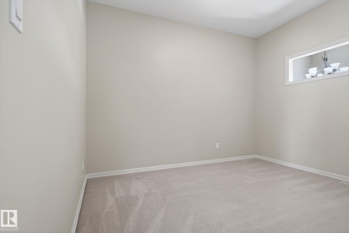 Bedroom featuring light gray carpet, neutral wall paint, white trim, and a high horizontal window with a chandelier visible in the background - 34 3003 34 Avenue, Edmonton, AB - Indoor Photo Showing Other Room
