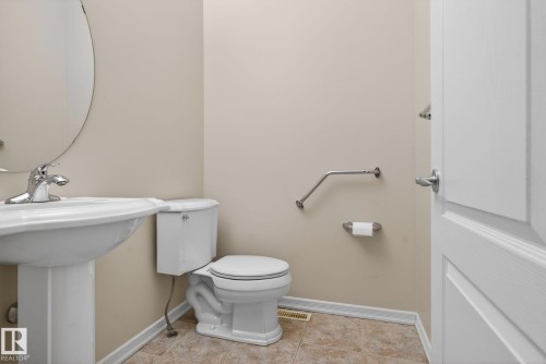 Pedestal sink with chrome faucet, oval wall mirror, and neutral wall paint - 34 3003 34 Avenue, Edmonton, AB - Indoor Photo Showing Bathroom