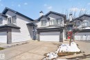 Two-story townhouse exterior with light siding, dark trim, an attached garage, a red entry door, and a chimney feature - 34 3003 34 Avenue, Edmonton, AB  - Outdoor With Facade 