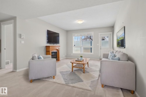Living area featuring light gray wall paint, recessed lighting, white trim, a wood-finish fireplace mantel with an electric insert, and carpet flooring - 34 3003 34 Avenue, Edmonton, AB - Indoor Photo Showing Living Room With Fireplace