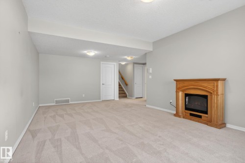 Spacious interior room featuring light gray walls, patterned carpet flooring, and white baseboards - 34 3003 34 Avenue, Edmonton, AB - Indoor