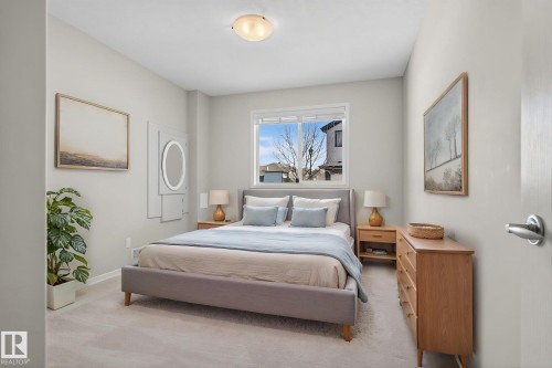 Bedroom featuring neutral color palette, light gray carpeting, window with natural light, a flush mount ceiling light, and built-in closet with an oval mirror - 34 3003 34 Avenue, Edmonton, AB - Indoor Photo Showing Bedroom