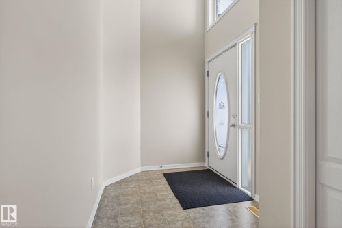 Entryway featuring a decorative oval glass door with sidelight, transom windows, neutral wall tones, and ceramic tile flooring - 34 3003 34 Avenue, Edmonton, AB - Indoor Photo Showing Other Room