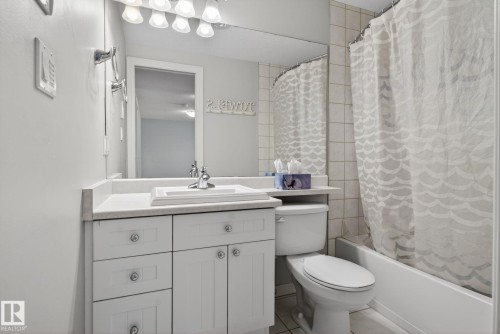 Bathroom featuring a white vanity with integrated sink, chrome faucet, wall-mounted mirror, and overhead vanity lighting - 34 3003 34 Avenue, Edmonton, AB - Indoor Photo Showing Bathroom