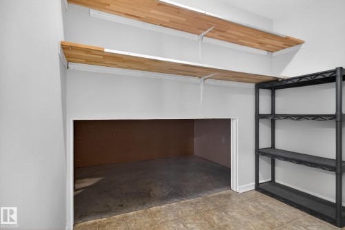 Utility space featuring two wood-finish floating shelves, light gray painted walls, and square tile flooring - 34 3003 34 Avenue, Edmonton, AB - Indoor With Storage