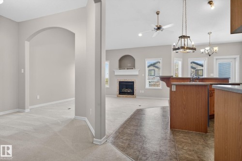 Open-concept interior featuring an arched entryway, light neutral wall tones, and a carpeted room - 34 3003 34 Avenue, Edmonton, AB - Indoor With Fireplace