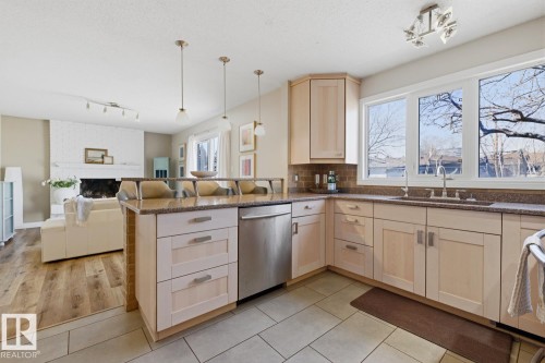 Kitchen featuring light wood cabinetry, granite-finish countertops, stainless steel dishwasher, tile flooring, and a stone-finish backsplash - 17604 85 Avenue, Edmonton, AB - Indoor Photo Showing Kitchen