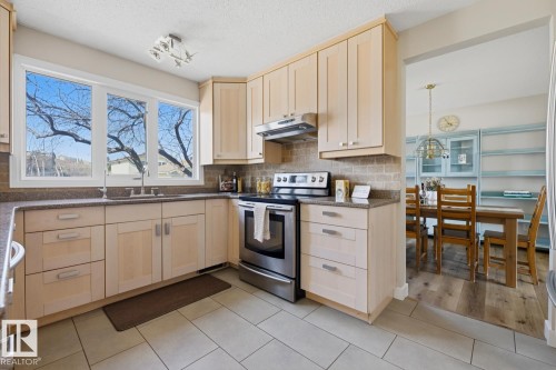 Light-toned cabinetry kitchen featuring stainless steel appliances, a tile backsplash, and stone-finish countertops - 17604 85 Avenue, Edmonton, AB - Indoor Photo Showing Kitchen