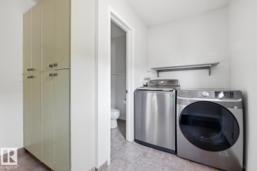 Laundry area featuring a side-by-side washer and dryer, tile flooring, built-in storage cabinetry, and wall-mounted shelving - 17604 85 Avenue, Edmonton, AB - Indoor Photo Showing Laundry Room