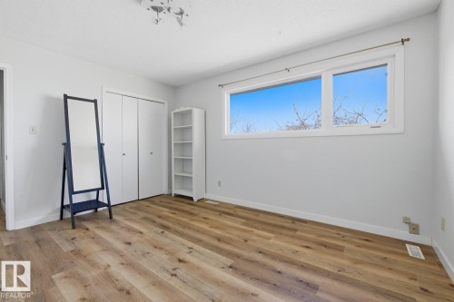 Spacious room featuring wood-finish flooring, light-toned walls, and a large window - 17604 85 Avenue, Edmonton, AB - Indoor Photo Showing Other Room