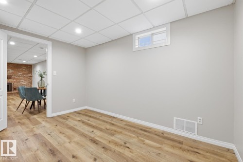 Spacious room with wood-finish flooring, light grey walls, white trim, and a drop ceiling with recessed lighting - 17604 85 Avenue, Edmonton, AB - Indoor Photo Showing Other Room