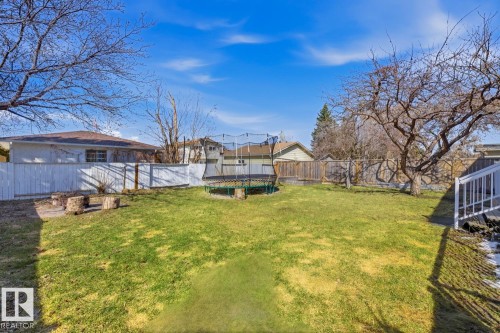 Expansive backyard with a manicured lawn, established trees, and a white privacy fence - 17604 85 Avenue, Edmonton, AB - Outdoor