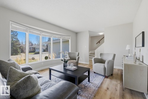 Spacious living area featuring a large bay window, light wood-finish flooring, and light gray wall tones - 17604 85 Avenue, Edmonton, AB - Indoor Photo Showing Living Room