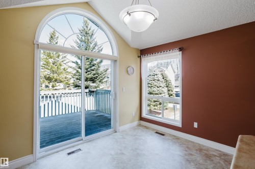 Vaulted ceiling with an arched transom window above sliding patio doors leading to an exterior deck - 9 102 Bridgeport Crossing, Leduc, AB - Indoor Photo Showing Other Room