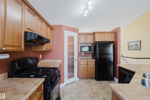 Kitchen featuring light wood cabinetry, a black gas range, and a black refrigerator - 9 102 Bridgeport Crossing, Leduc, AB - Indoor Photo Showing Kitchen With Double Sink