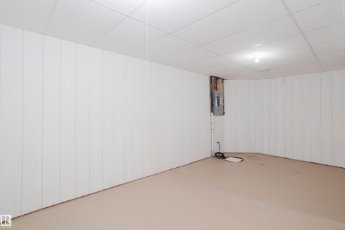Room featuring white vertical paneling and a suspended ceiling system perfect for a potential workshop - 9 102 Bridgeport Crossing, Leduc, AB - Indoor Photo Showing Other Room