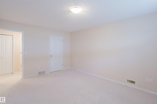 Spacious room with light-toned carpet flooring, light-colored walls, and white trim - 9 102 Bridgeport Crossing, Leduc, AB - Indoor Photo Showing Other Room