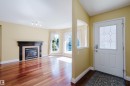 Foyer with a white entry door featuring window to let in more light, leading to a living area with wood-finish flooring - 9 102 Bridgeport Crossing, Leduc, AB  - Indoor Photo Showing Living Room With Fireplace 