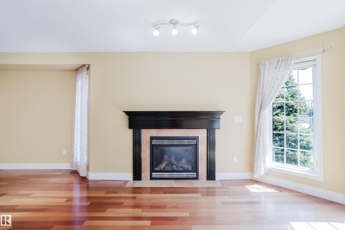 Living space featuring a prominent fireplace with a black mantel and tiled surround - 9 102 Bridgeport Crossing, Leduc, AB - Indoor Photo Showing Living Room With Fireplace