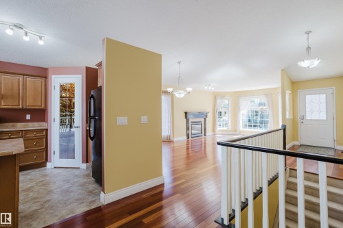Open-concept living space with wood-finish flooring, a detailed fireplace, and a bay window - 9 102 Bridgeport Crossing, Leduc, AB - Indoor Photo Showing Other Room
