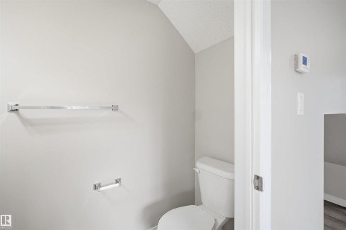 Bathroom featuring a white toilet, light gray walls, and textured ceiling - 33 7385 Edgemont Way Nw, Edmonton, AB - Indoor Photo Showing Bathroom