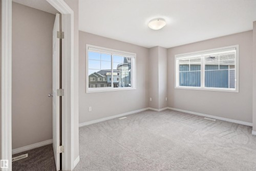 Spacious room featuring multiple windows, neutral wall paint, light-colored carpeting, and a flush-mount ceiling light fixture - 33 7385 Edgemont Way Nw, Edmonton, AB - Indoor Photo Showing Other Room