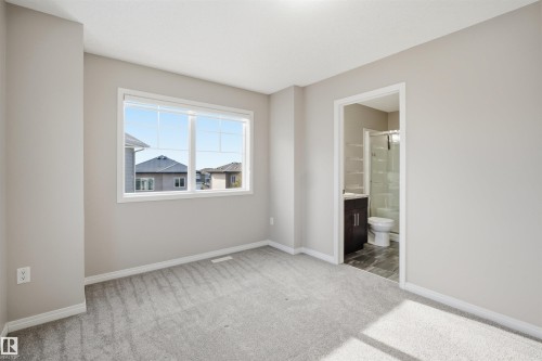 Carpeted room with a large multi-pane window and light gray walls - 33 7385 Edgemont Way Nw, Edmonton, AB - Indoor Photo Showing Other Room