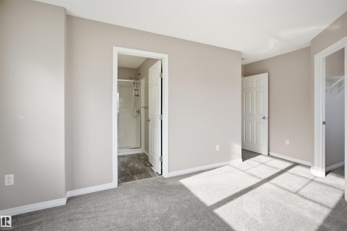 Spacious room featuring light neutral wall paint, white trim, and gray carpet flooring - 33 7385 Edgemont Way Nw, Edmonton, AB - Indoor Photo Showing Other Room