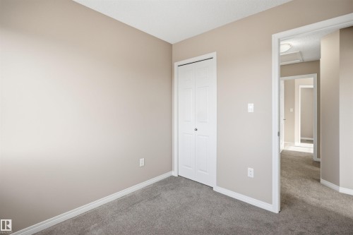 Room featuring neutral-toned walls, grey carpet flooring, white baseboards, and a bi-fold closet door - 33 7385 Edgemont Way Nw, Edmonton, AB - Indoor Photo Showing Other Room