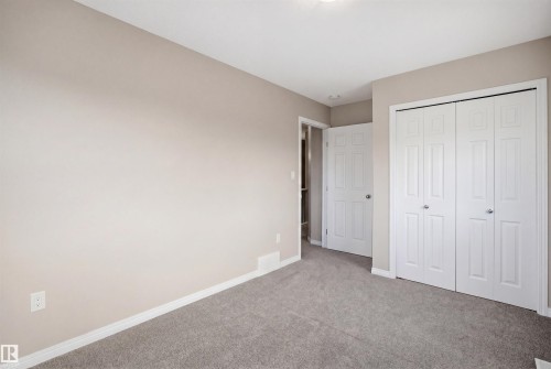 Room featuring light neutral wall paint, gray carpeting, white trim, and a white bi-fold closet - 33 7385 Edgemont Way Nw, Edmonton, AB - Indoor