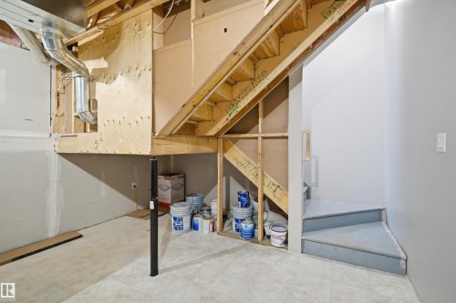 Unfinished lower level featuring exposed wood framing, ductwork, a structural support column, and a painted staircase - 33 7385 Edgemont Way Nw, Edmonton, AB - Indoor Photo Showing Basement